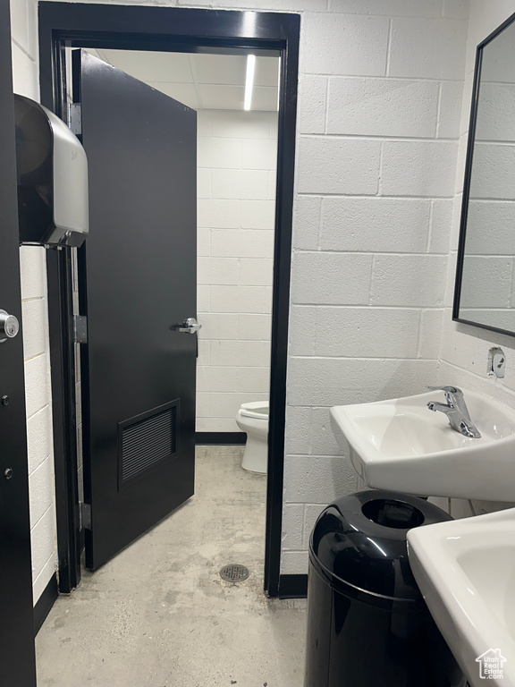 Bathroom featuring sink, toilet, and concrete flooring