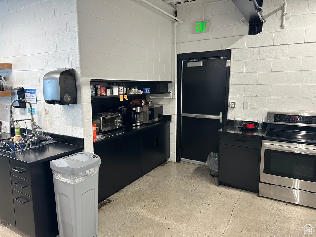 Kitchen with stainless steel electric stove and black fridge