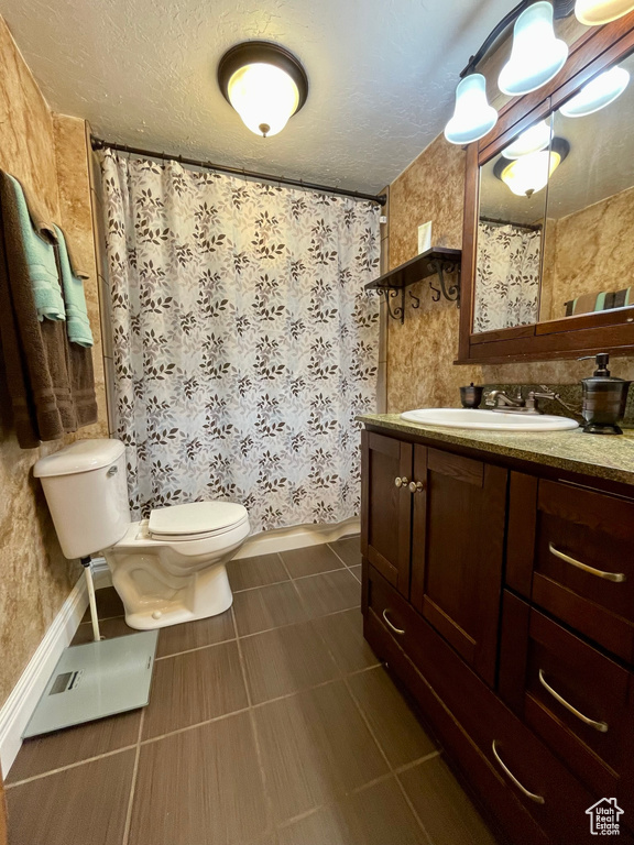 Bathroom featuring tile patterned flooring, toilet, a textured ceiling, and vanity