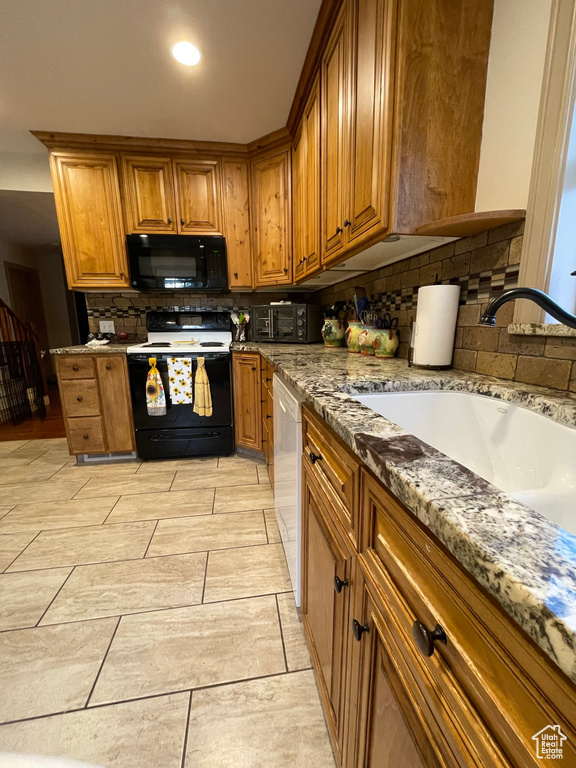 Kitchen with light tile patterned flooring, decorative backsplash, light stone counters, and white appliances