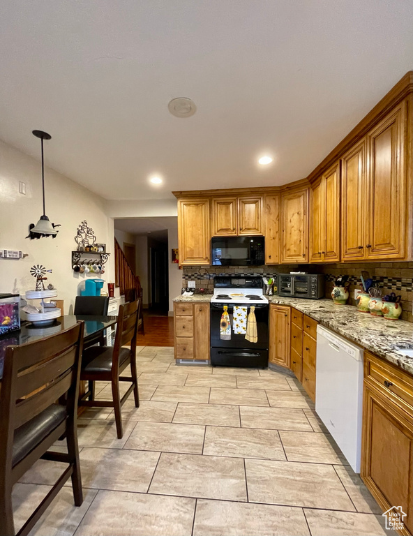 Kitchen featuring tasteful backsplash, hanging light fixtures, light stone countertops, light tile patterned floors, and white appliances