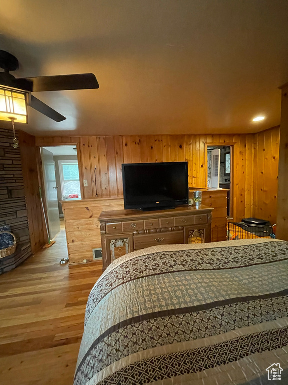 Living room with ceiling fan, light wood-type flooring, and wooden walls