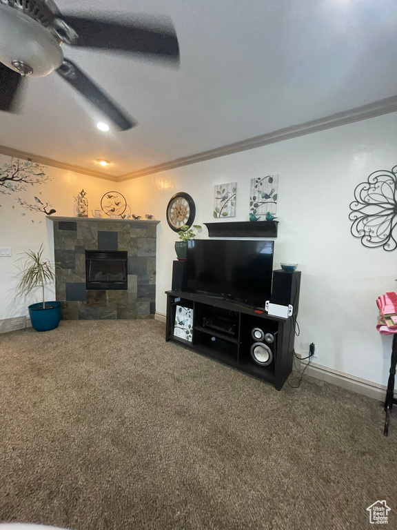 Carpeted living room with ceiling fan, ornamental molding, and a fireplace