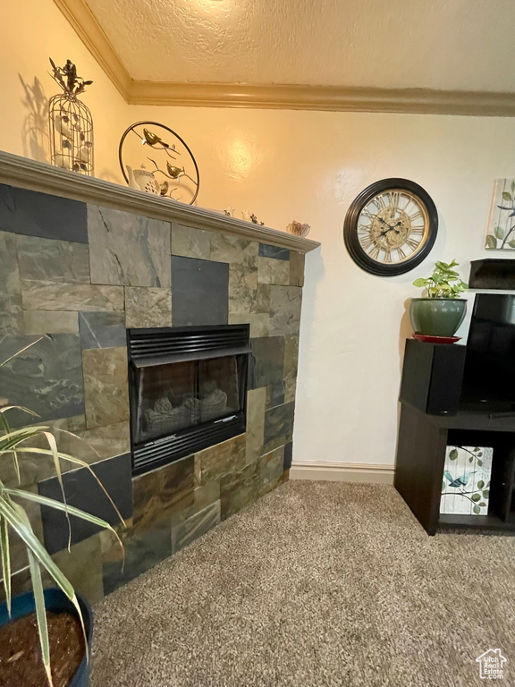 Living area with a textured ceiling, tile walls, ornamental molding, and a tile fireplace