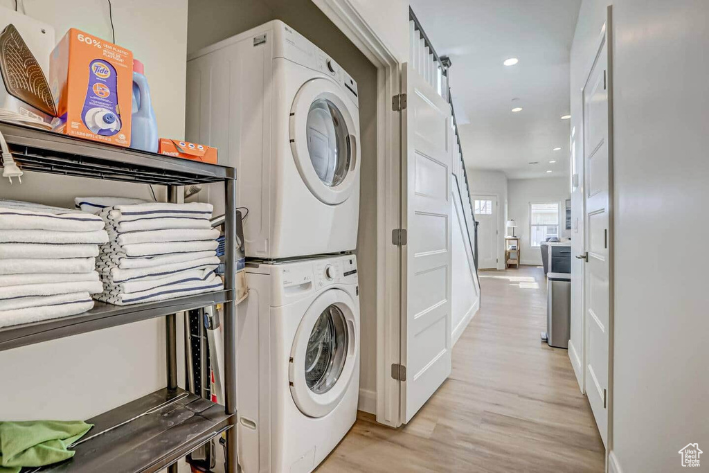 Laundry room with light wood-type flooring and stacked washing maching and dryer
