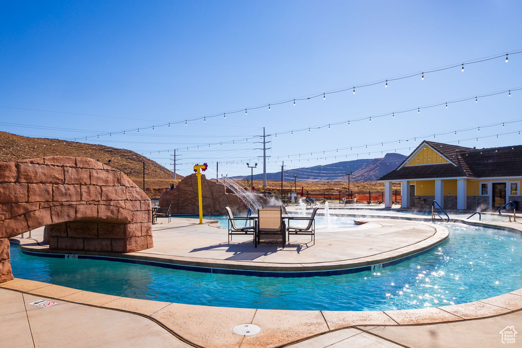 View of pool with a mountain view, a patio, and pool water feature