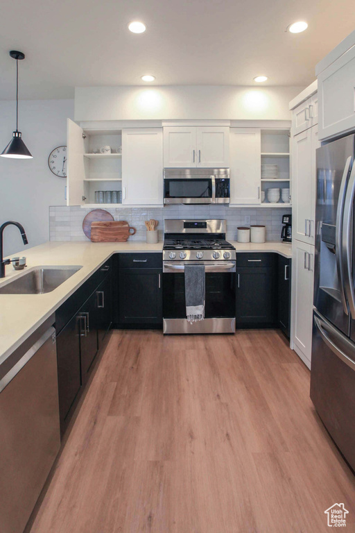 Kitchen featuring backsplash, white cabinetry, light hardwood / wood-style floors, sink, and stainless steel appliances