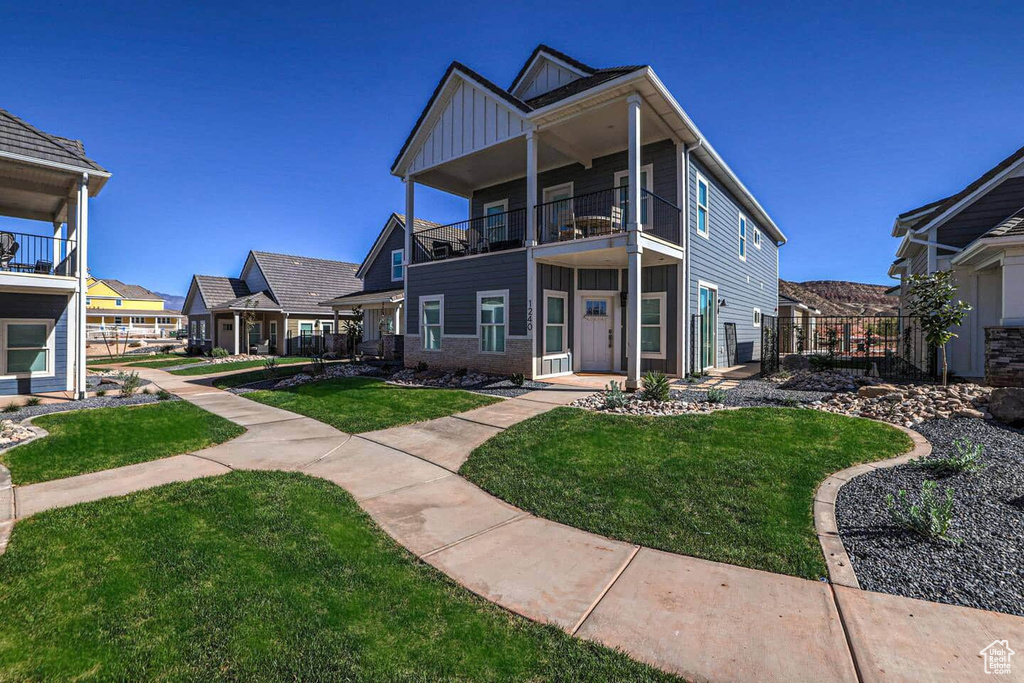 Back of property with a balcony and a lawn
