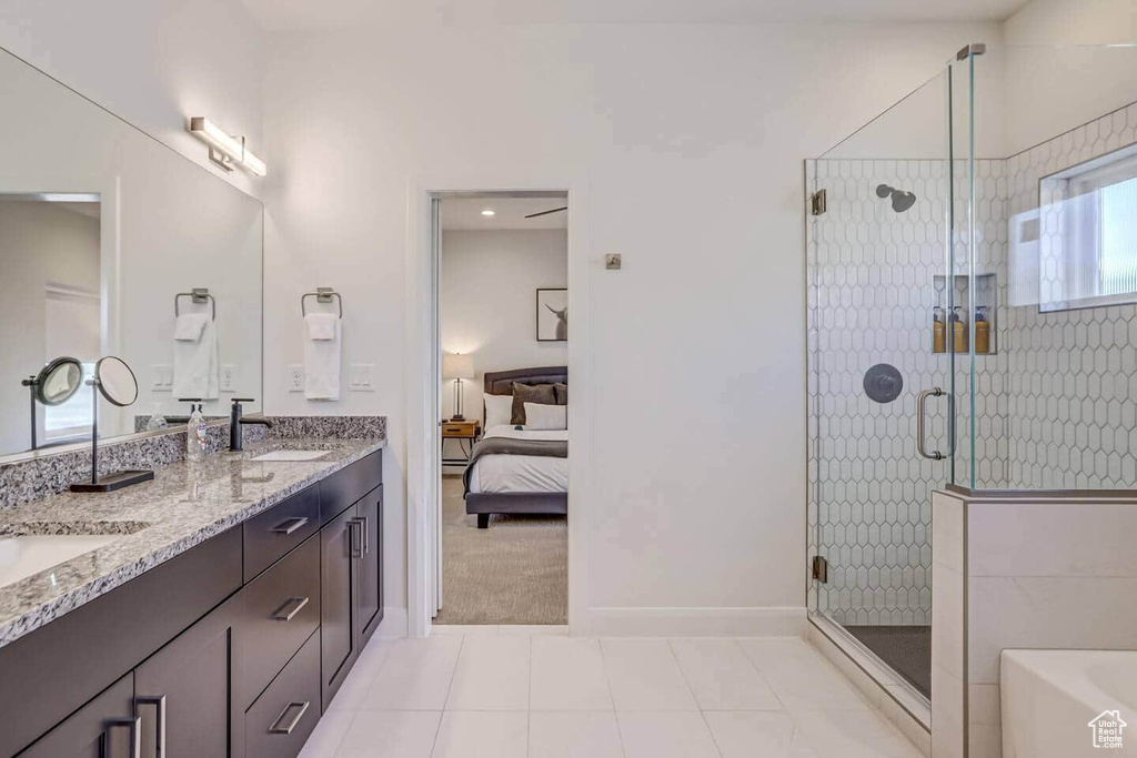Bathroom with tile patterned flooring, a shower with door, and vanity