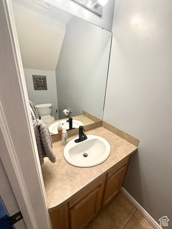 Bathroom with tile patterned flooring, toilet, vanity, and lofted ceiling