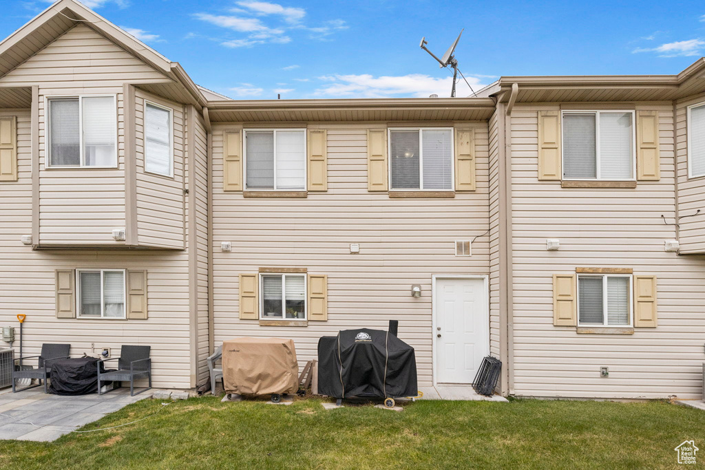Rear view of property featuring a lawn, central air condition unit, and a patio