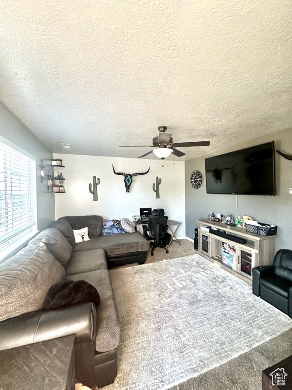 Living room with ceiling fan, carpet flooring, and a textured ceiling