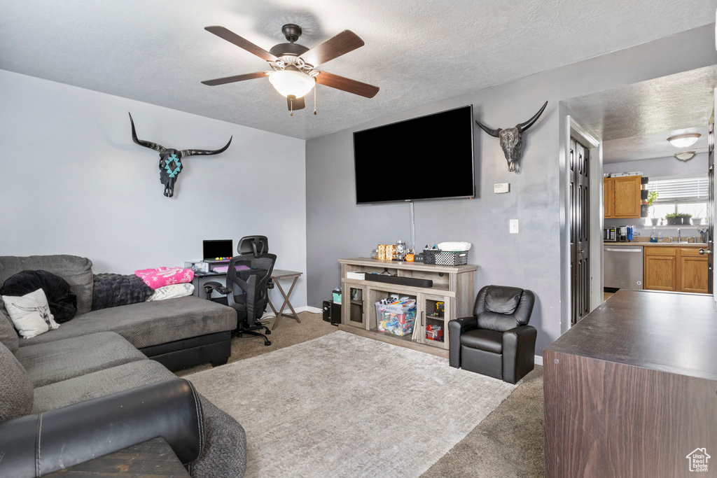 Carpeted living room with a textured ceiling and ceiling fan