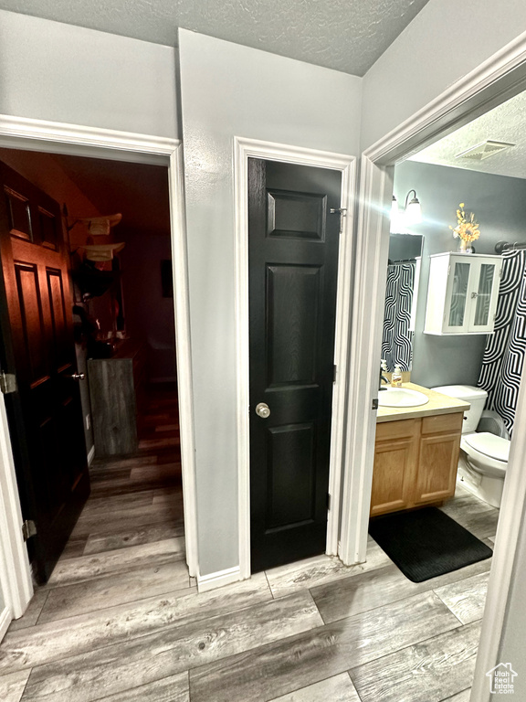 Bathroom with hardwood / wood-style flooring, a textured ceiling, vanity, and toilet