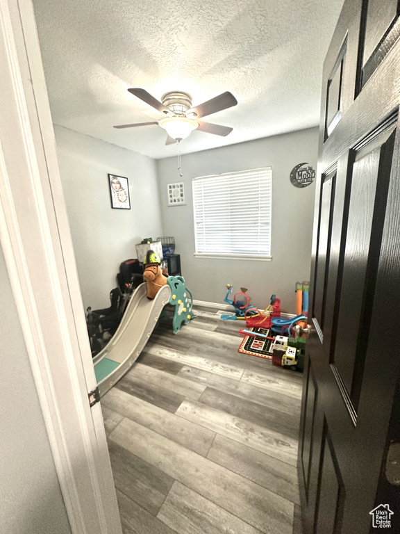 Playroom with ceiling fan, wood-type flooring, and a textured ceiling