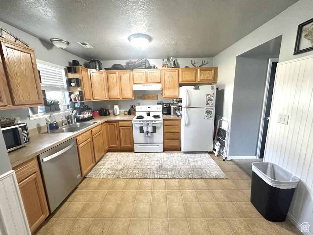 Kitchen featuring appliances with stainless steel finishes, a textured ceiling, light tile patterned floors, and sink