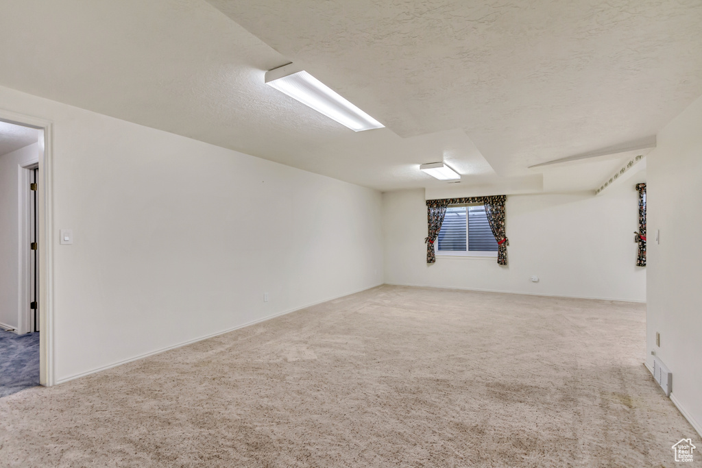 Unfurnished room featuring light carpet and a textured ceiling