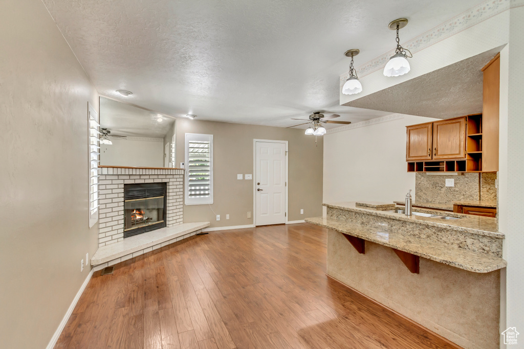 Kitchen with a textured ceiling, light hardwood / wood-style floors, and a brick fireplace