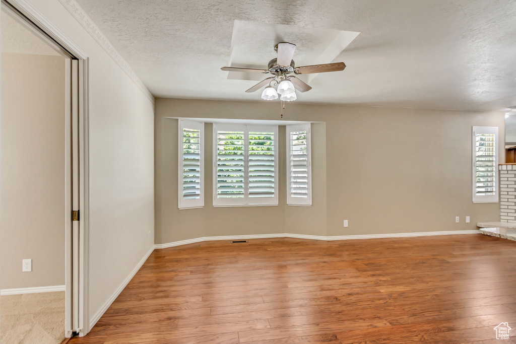 Empty room featuring a textured ceiling, light hardwood / wood-style flooring, and ceiling fan