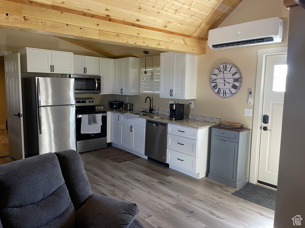 Kitchen featuring stainless steel appliances, light hardwood / wood-style floors, white cabinetry, a wall mounted air conditioner, and wood ceiling