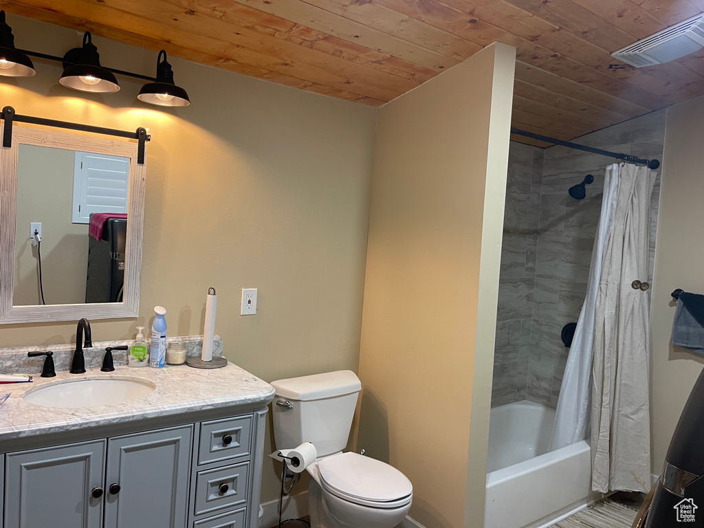 Full bathroom with wooden ceiling, toilet, shower / tub combo with curtain, and vanity