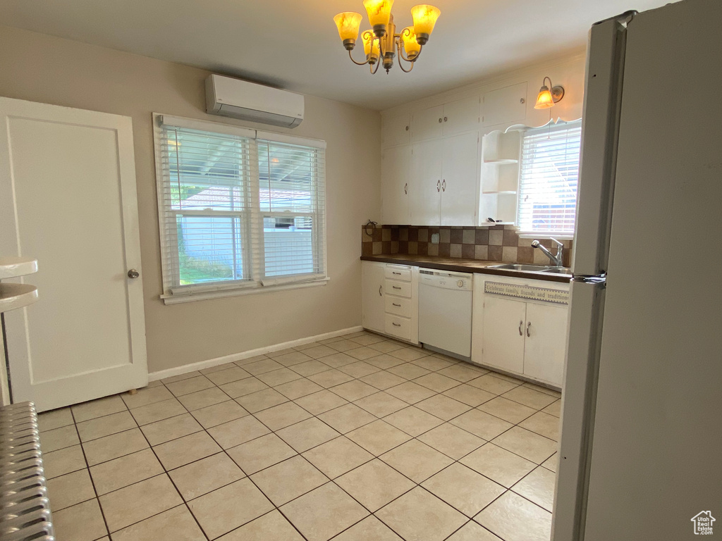 Kitchen with a wall mounted AC, tasteful backsplash, dishwasher, stainless steel fridge, and white cabinets