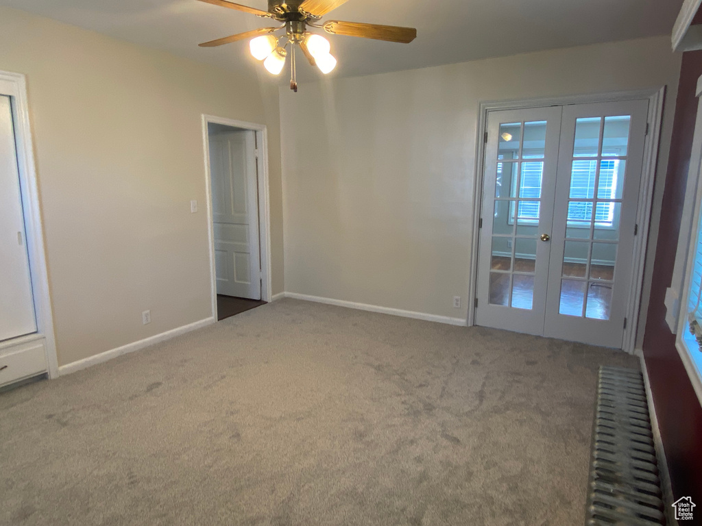 Carpeted spare room featuring ceiling fan and french doors