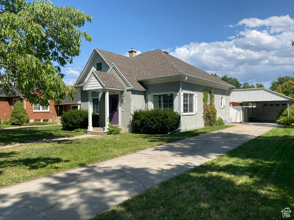 View of front of property with an outdoor structure, a garage, and a front yard