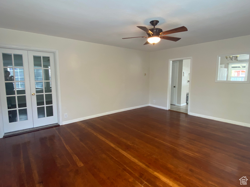 Empty room featuring dark hardwood / wood-style flooring, ceiling fan, and french doors