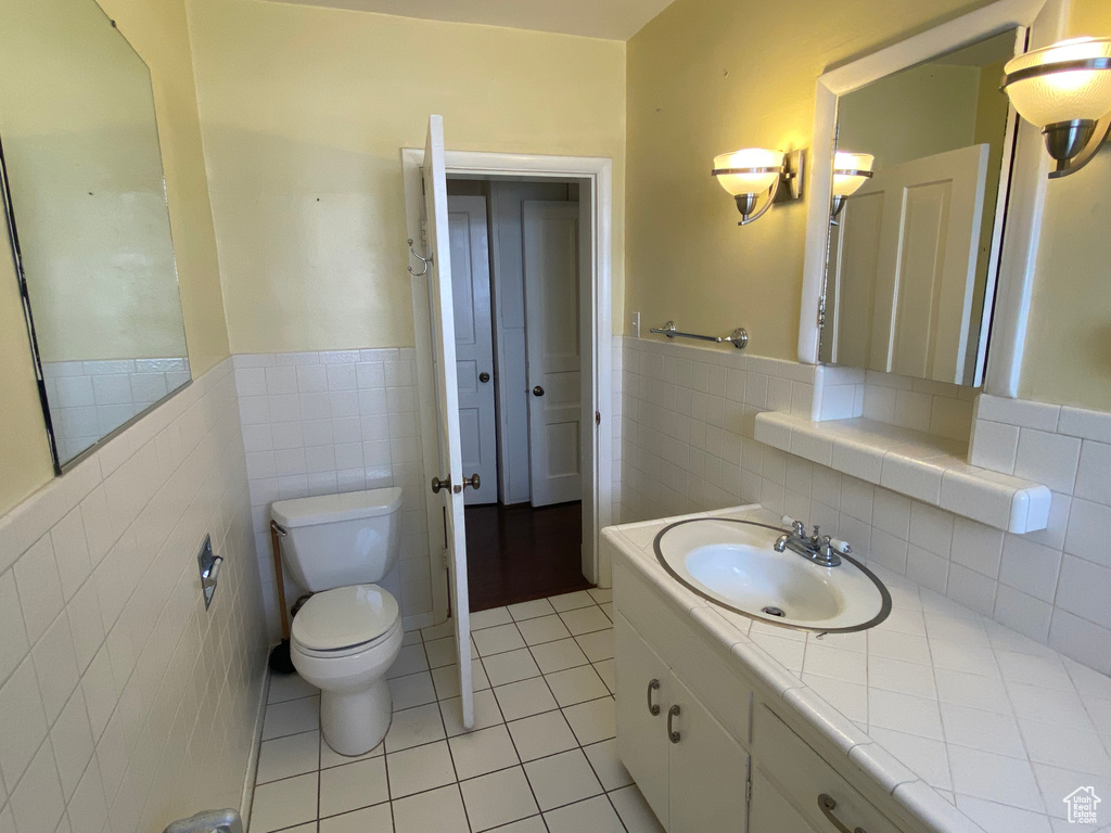 Bathroom with toilet, decorative backsplash, vanity, and tile walls