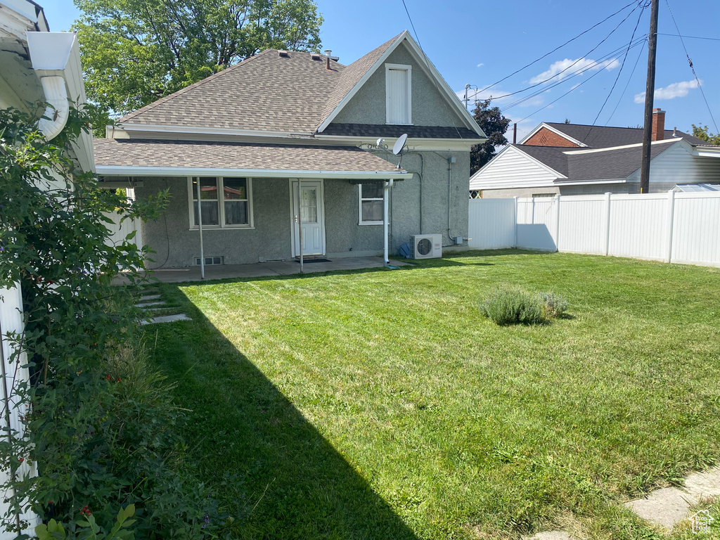 Back of property featuring central AC and a yard