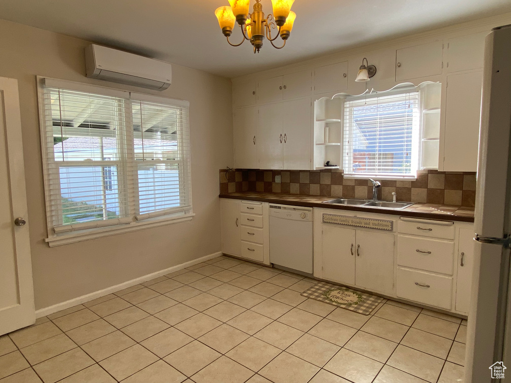 Kitchen with sink, tasteful backsplash, white cabinetry, dishwasher, and a wall unit AC