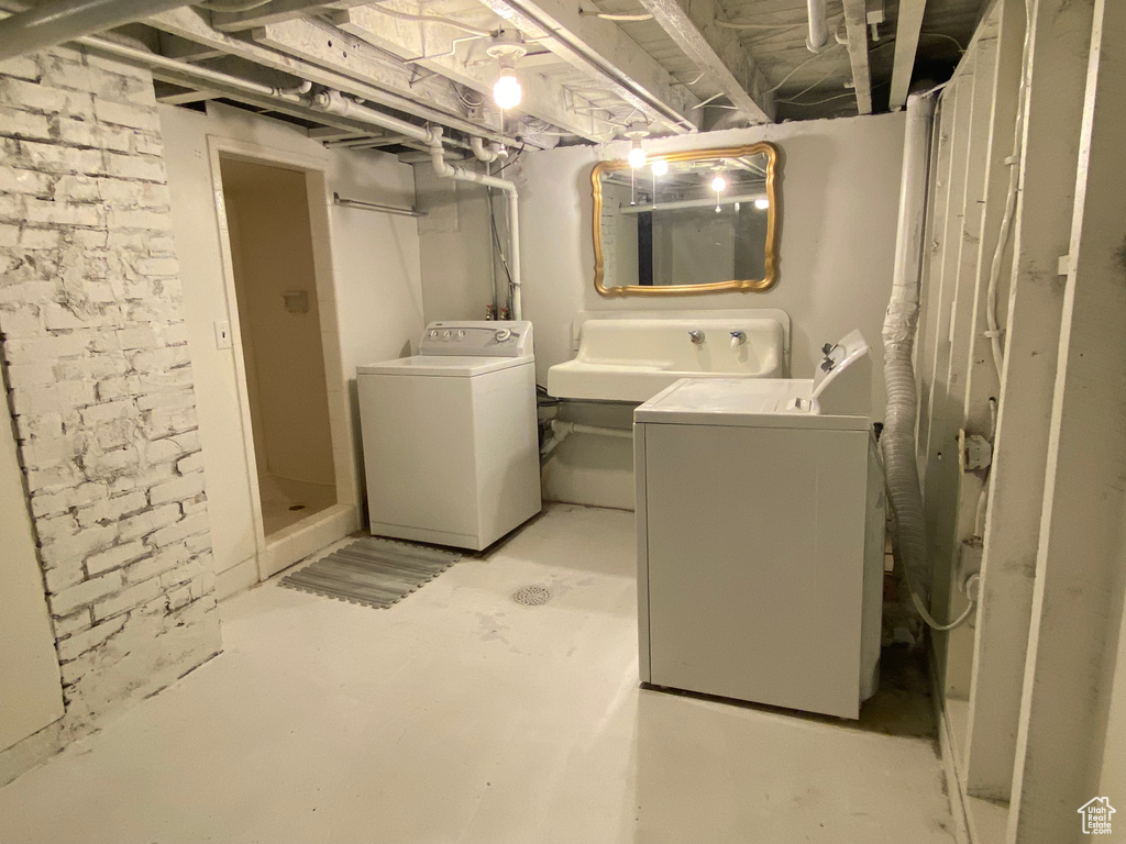 Laundry room featuring washing machine and clothes dryer and brick wall