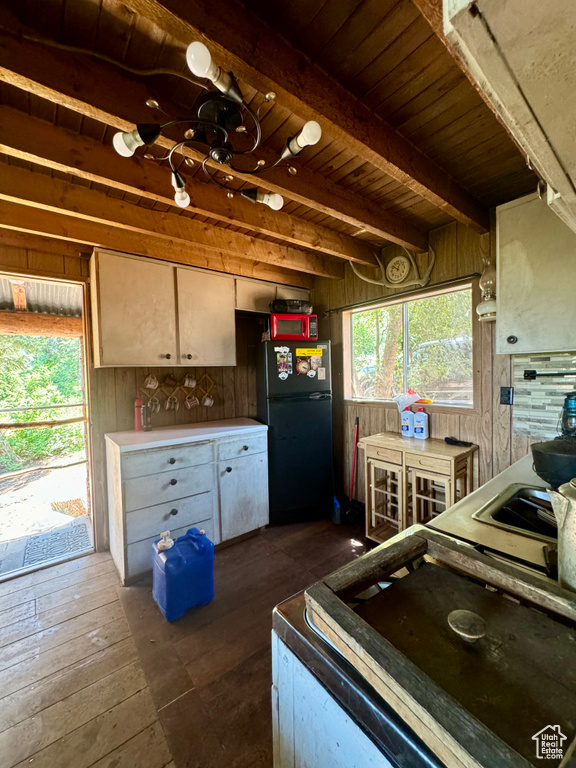 Kitchen with dark hardwood / wood-style flooring, wood walls, beam ceiling, wooden ceiling, and black refrigerator