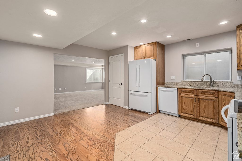 Kitchen featuring sink, light carpet, light stone countertops, and white appliances