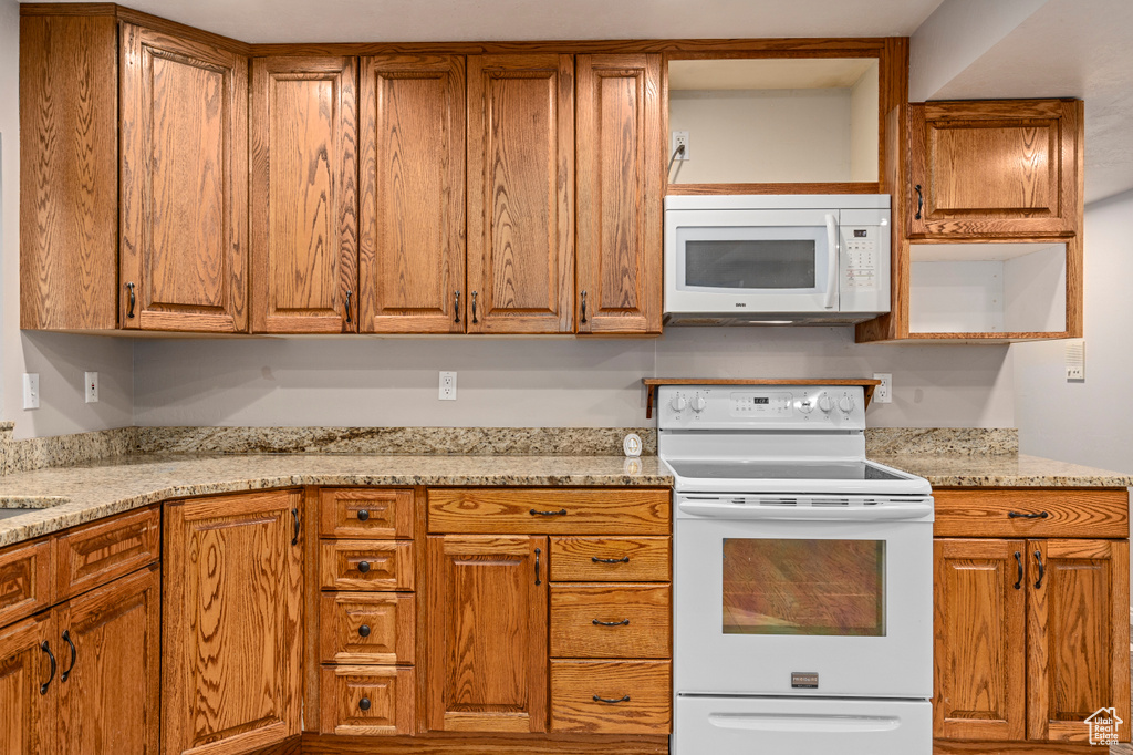 Kitchen featuring light stone countertops and white appliances