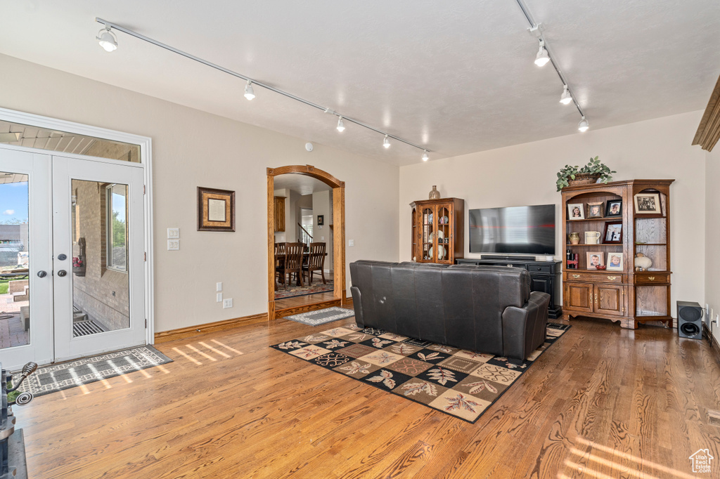 Living room with rail lighting, french doors, and hardwood / wood-style floors