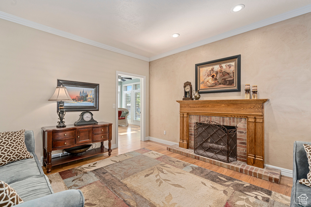 Living room with a fireplace, ornamental molding, and wood-type flooring