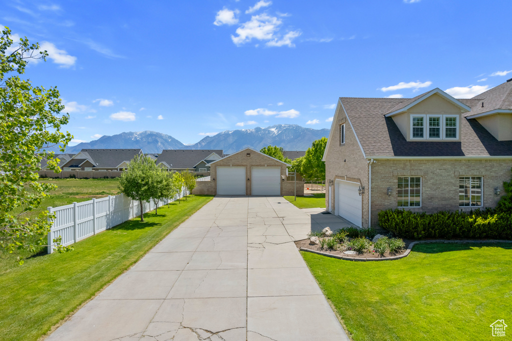 View of front of house with a garage, a front lawn, and a mountain view