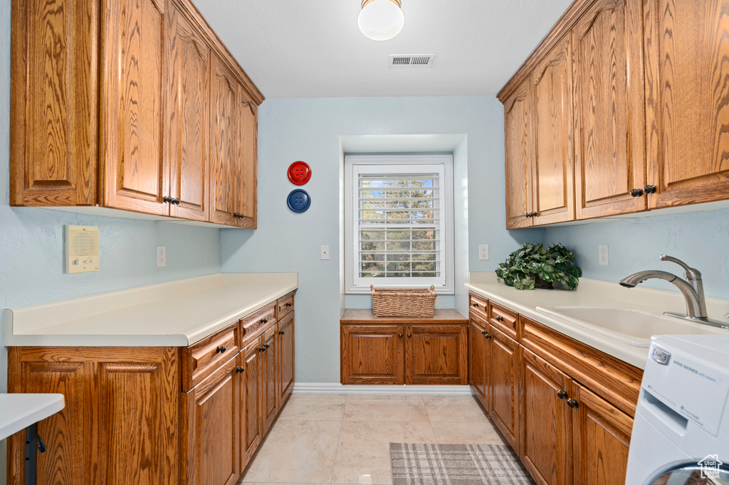 Kitchen featuring sink, washer / clothes dryer, and light tile patterned flooring