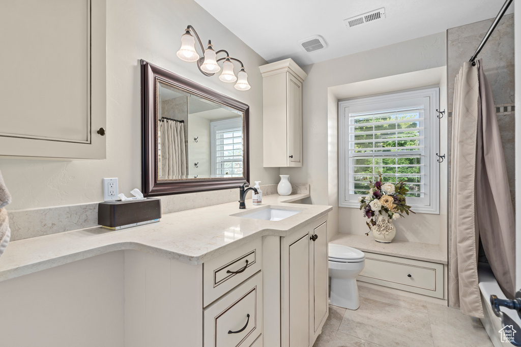 Full bathroom with tile patterned flooring, shower / tub combo with curtain, toilet, and vanity