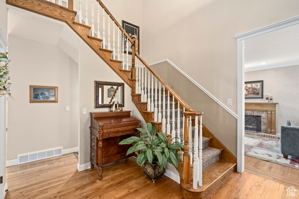 Stairway featuring hardwood / wood-style floors and a brick fireplace