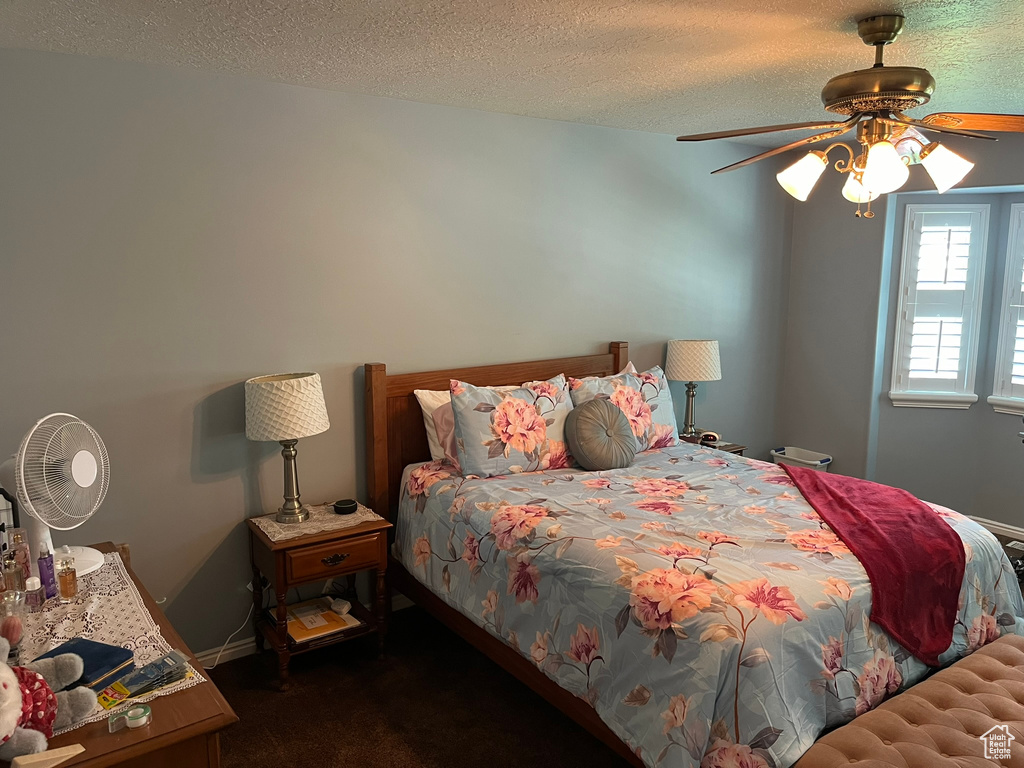 Carpeted bedroom featuring ceiling fan and a textured ceiling