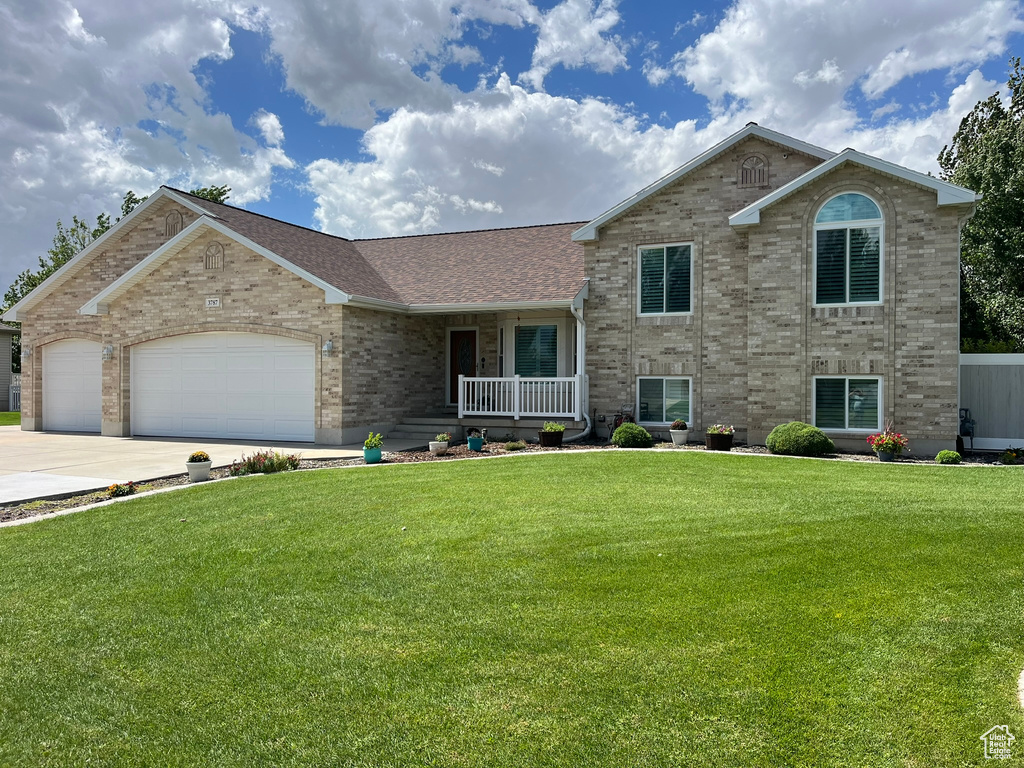 View of front facade featuring a garage, a porch, and a front yard