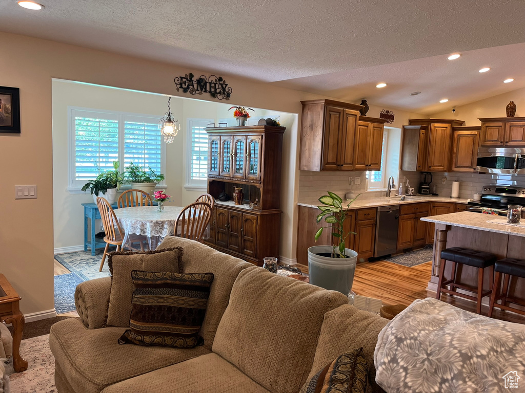 Living room featuring a textured ceiling, lofted ceiling, light hardwood / wood-style floors, and sink