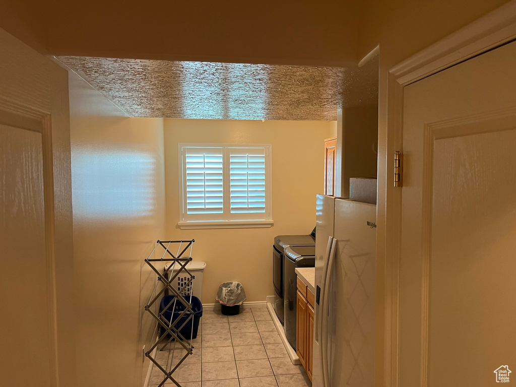 Clothes washing area with light tile patterned flooring and washing machine and dryer