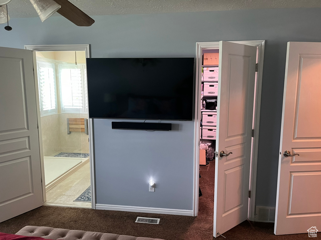 Living room with a textured ceiling, carpet floors, and ceiling fan