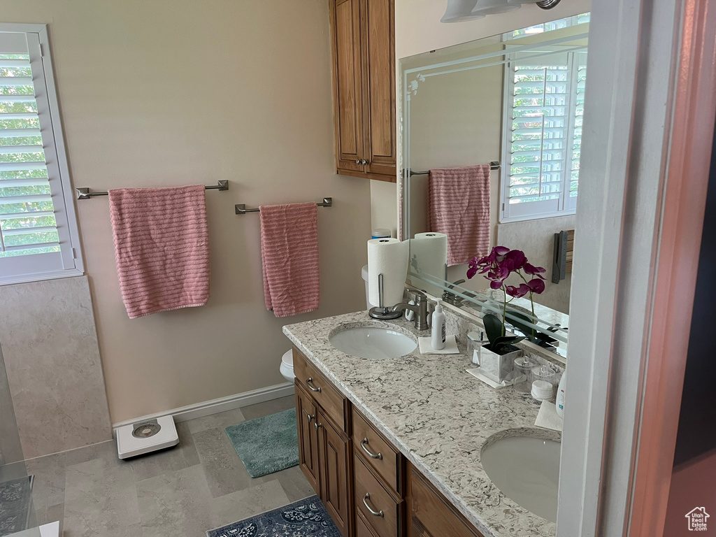 Bathroom featuring tile patterned floors, toilet, vanity, and a healthy amount of sunlight