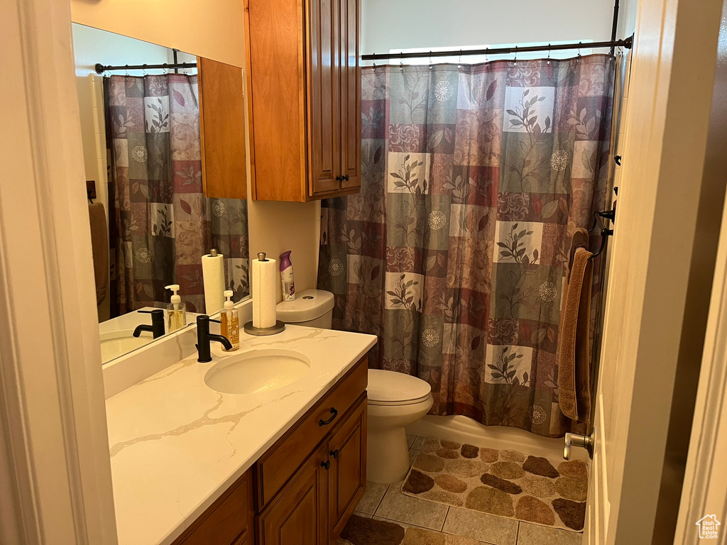 Bathroom with toilet, tile patterned flooring, vanity, and curtained shower