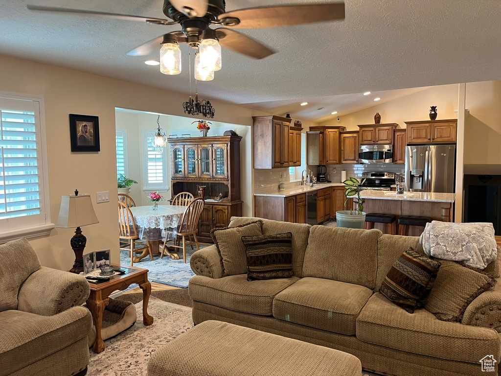 Living room with sink, ceiling fan, a textured ceiling, and vaulted ceiling